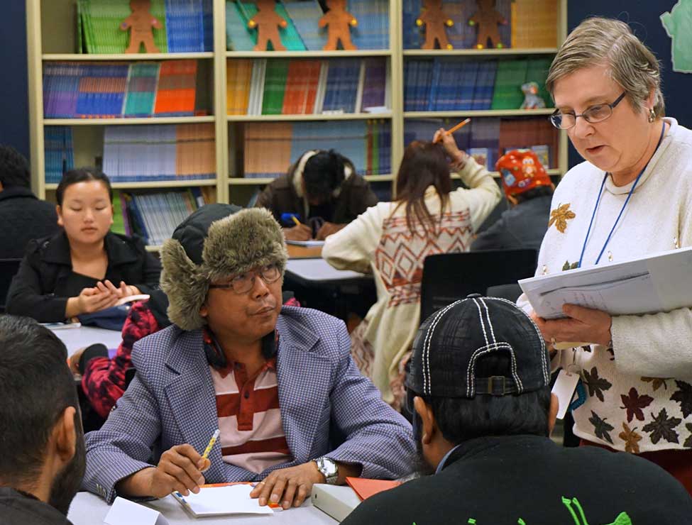 Students in classroom receiving worksheet from instructor