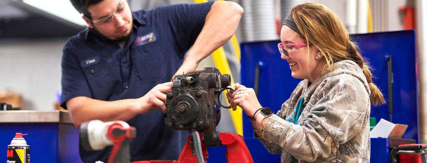 Mechanic and student working on machinery