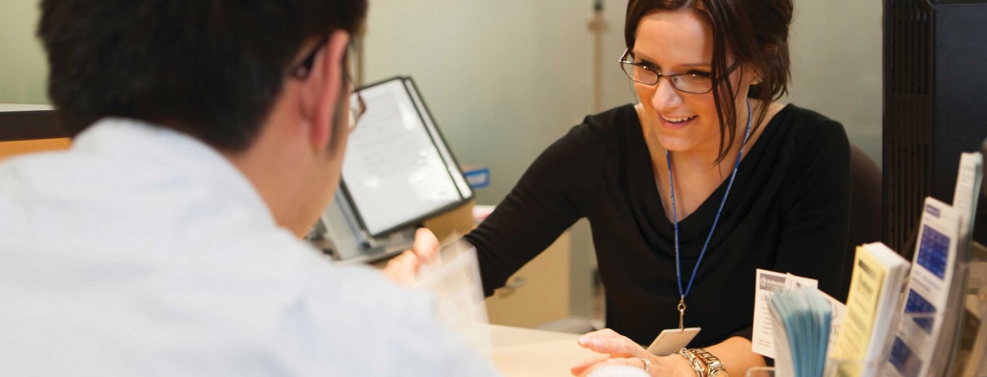 Faculty member chatting with person at office desk