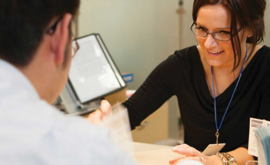 Faculty member chatting with person at office desk