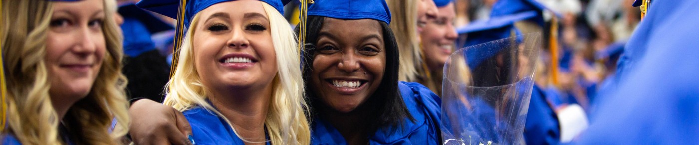 Graduates in cap and gowns smiling together