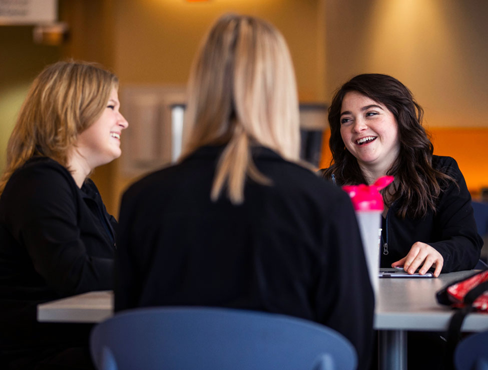 Three students in professional attire sitting together on campus