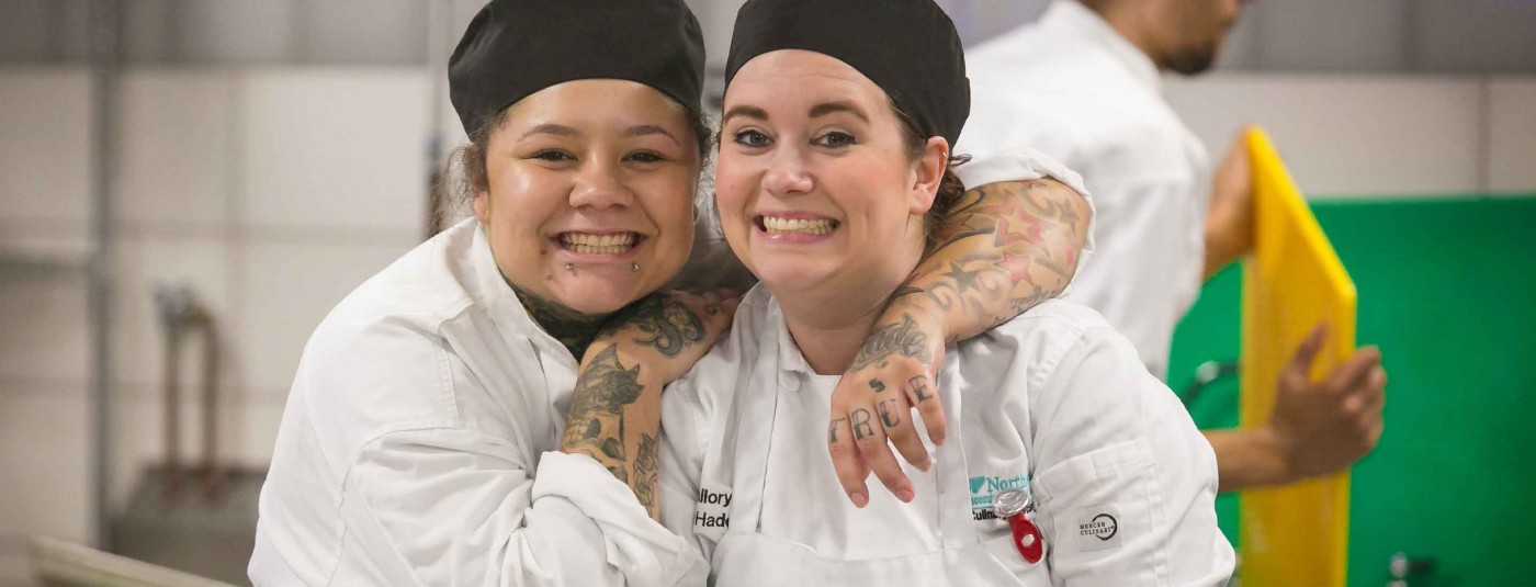 Two chefs in kitchen smiling