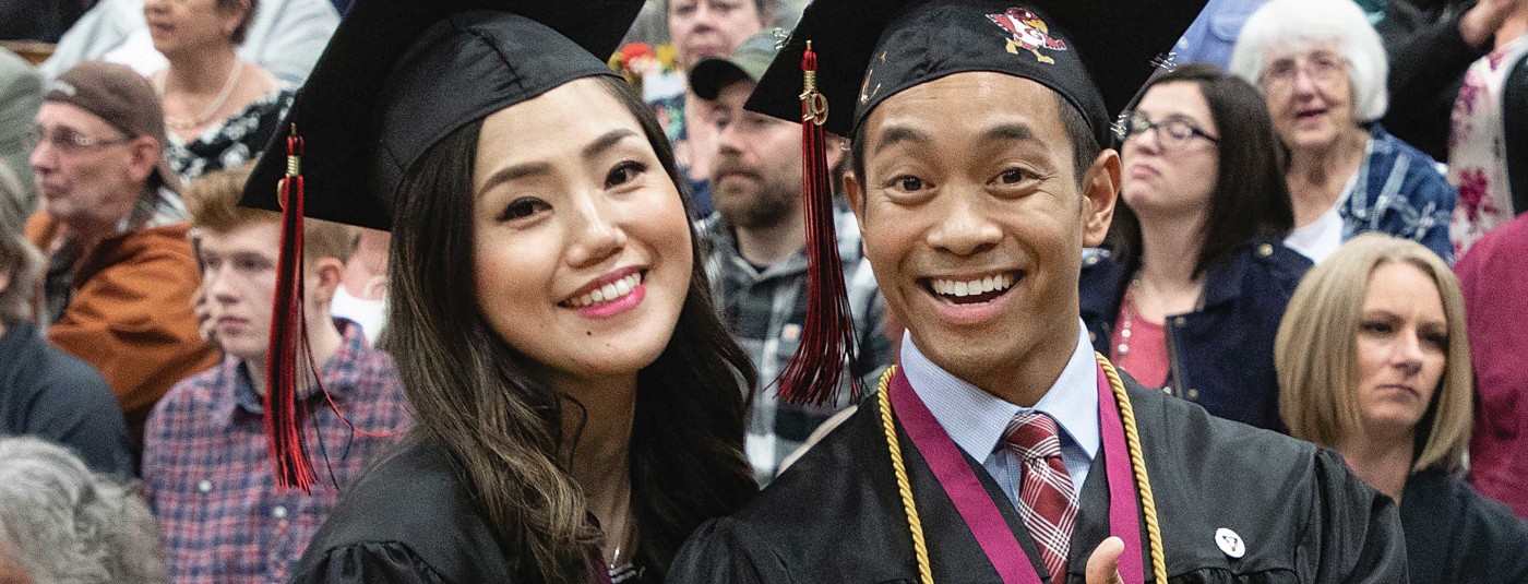 Two graduates on graduation day smiling together