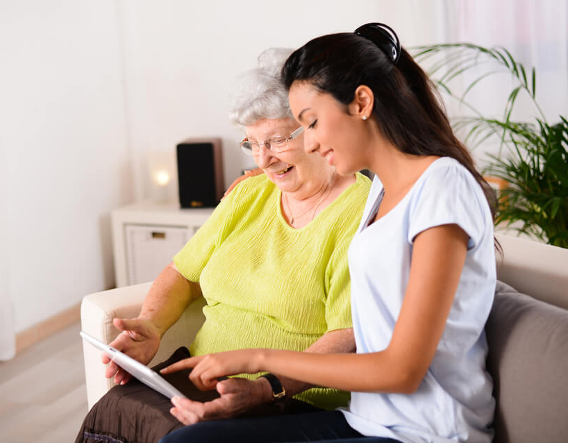 Personal care worker viewing a mobile device with an older woman